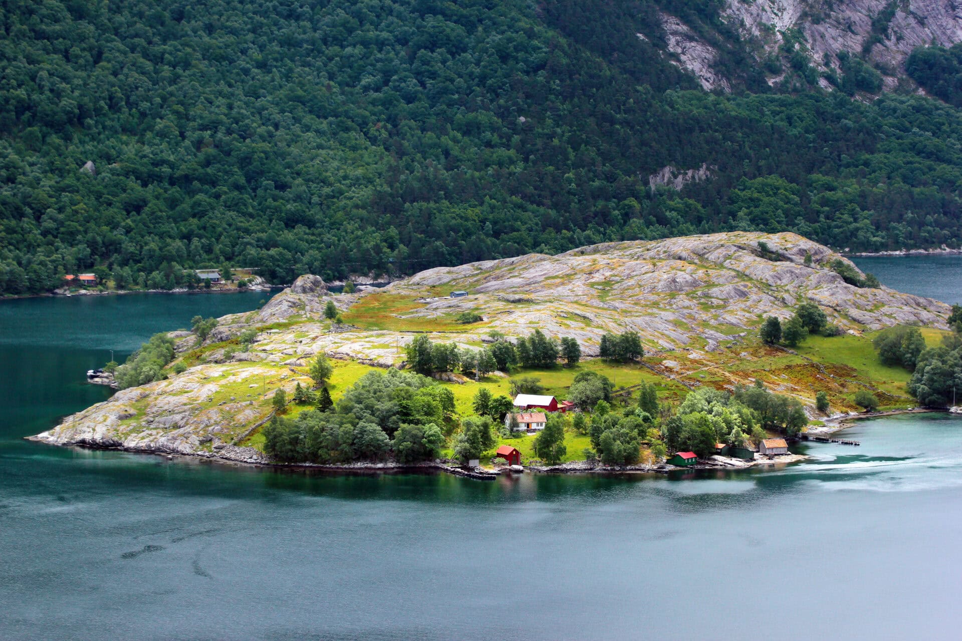 Secluded island with lush greenery, rocky terrain, and scenic fjord views in Norway.